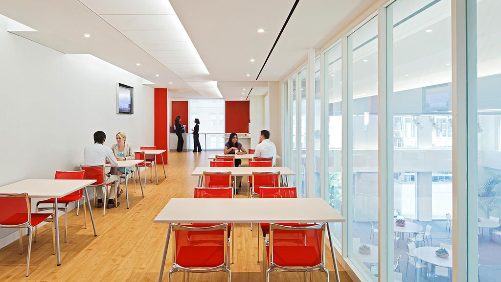 A group of people sitting at tables in a room with windows.