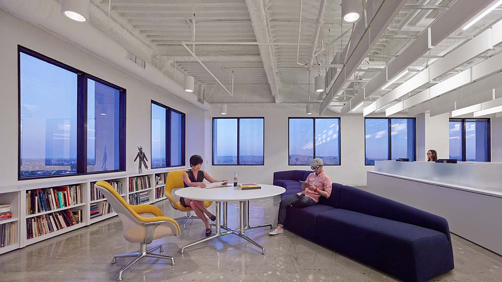 A man and woman sitting in a room with a table and chairs.
