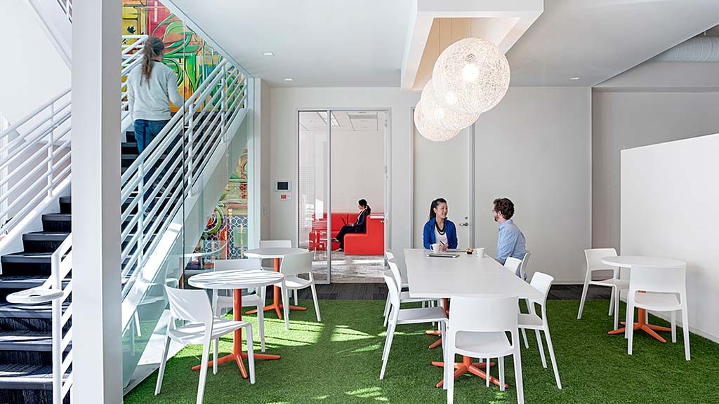 A group of people sitting at a table in a room with stairs.