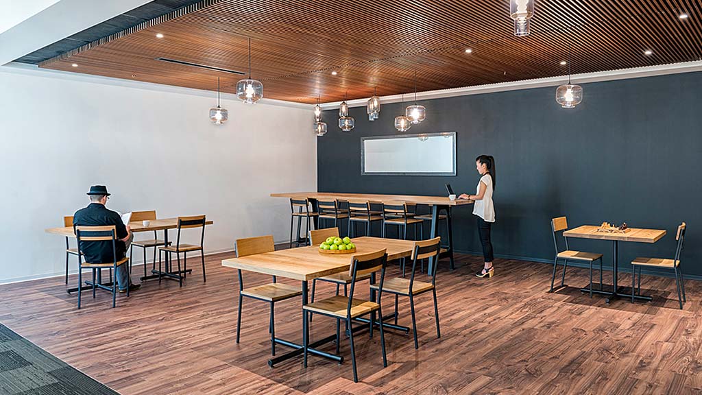 A person standing in a room with tables and chairs.