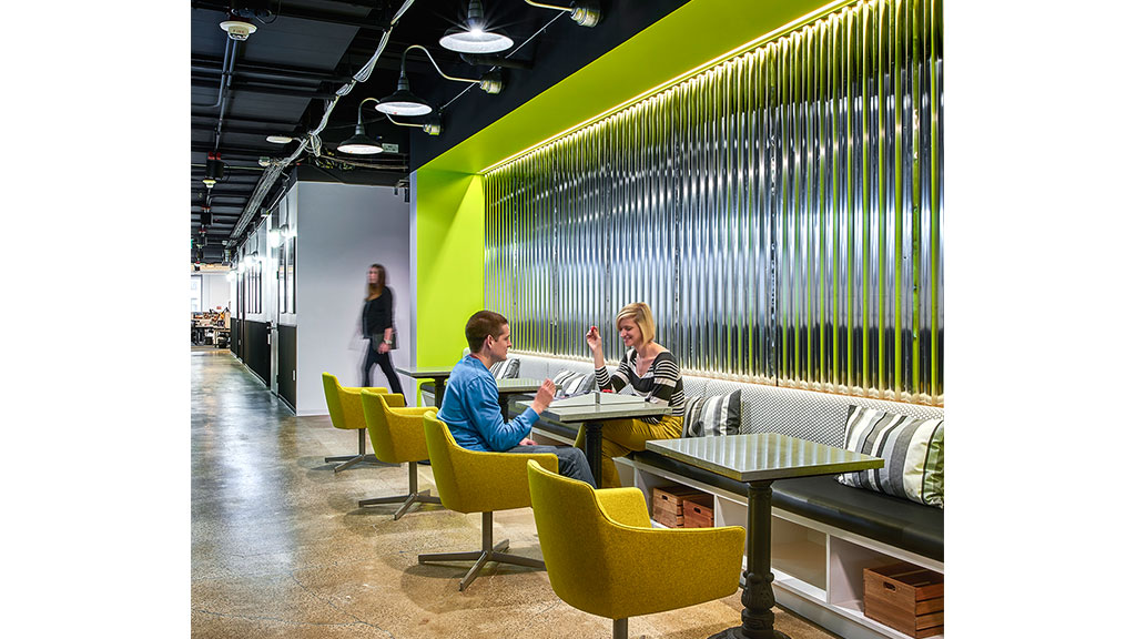 A man and woman sitting at a table in a room with green walls.