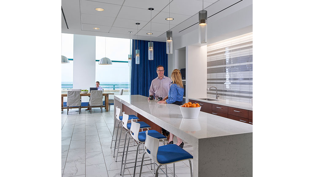 A man and woman standing at a table with a bowl of fruit.