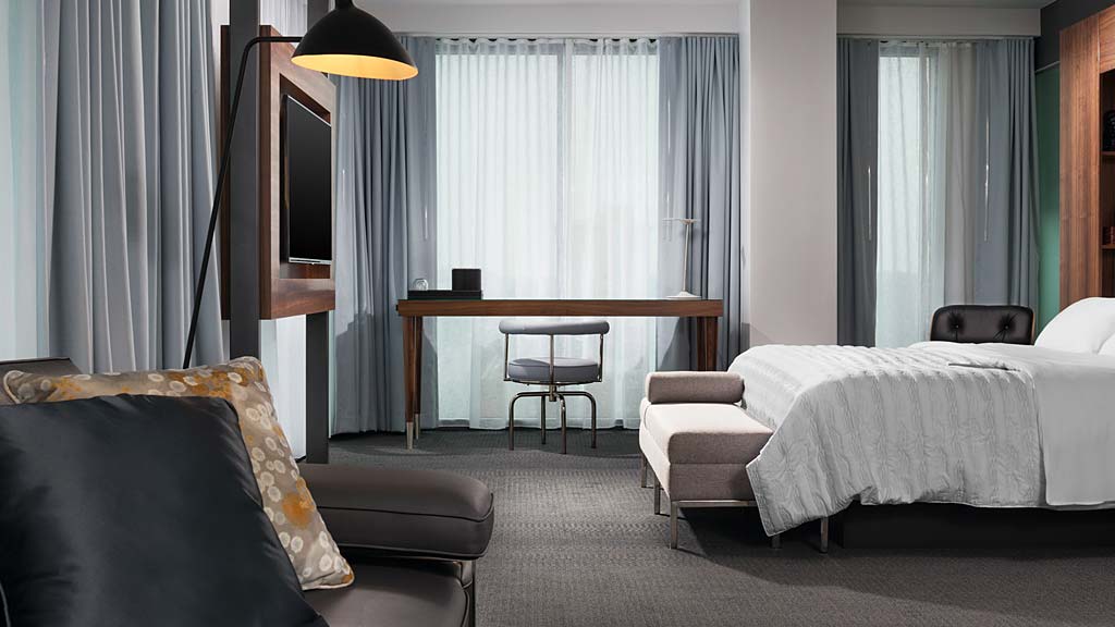A hotel room with a bed and a desk.
