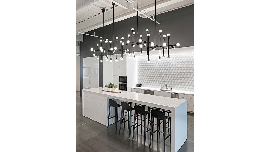 A kitchen with a large chandelier and a bar stool.