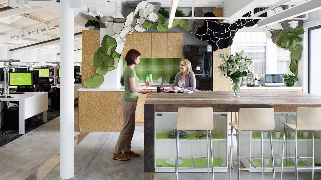 A man and woman standing at a counter in a room with plants.