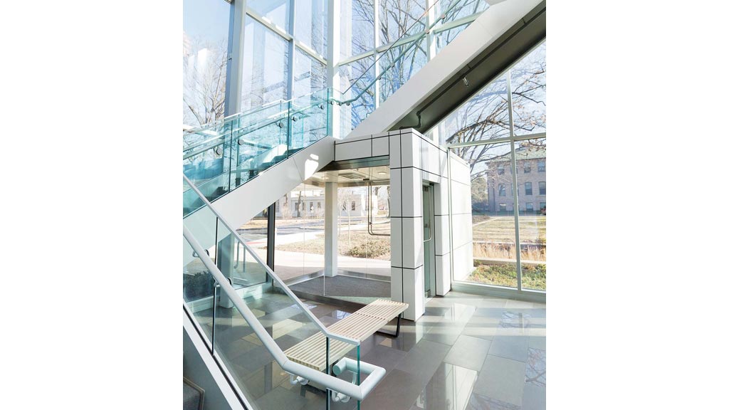 A glass walled building with a glass front and a bench.