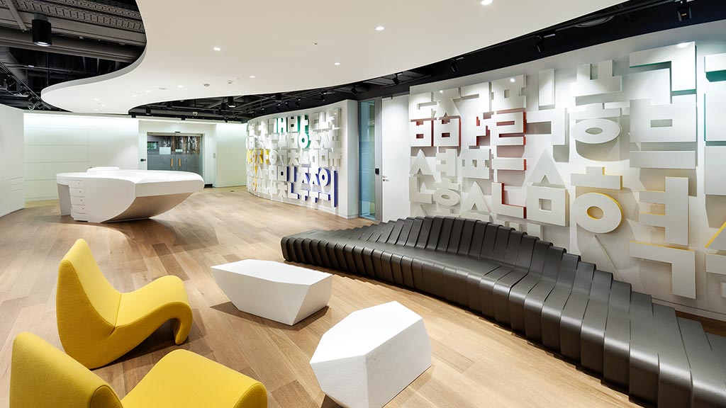 A room with a large white couch and yellow chairs.