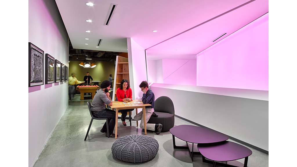 A group of people sitting at a table in a room with pink walls.
