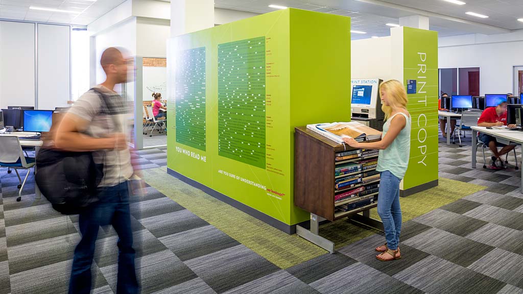 A man and a woman at a table with a green board.
