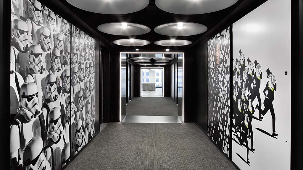 A hallway with a ceiling fan and a door with a light on the ceiling.