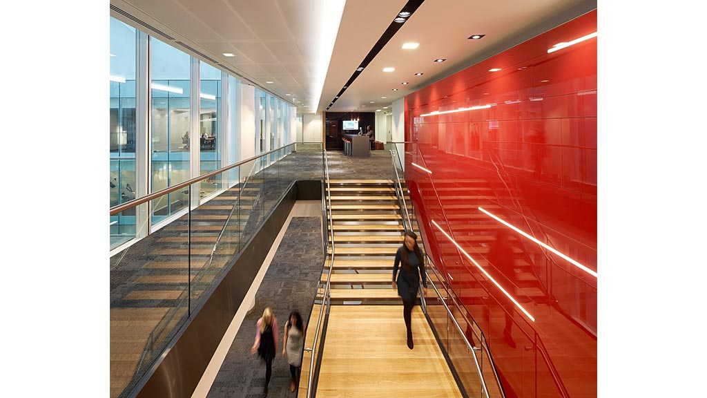 People walking down a long escalator.