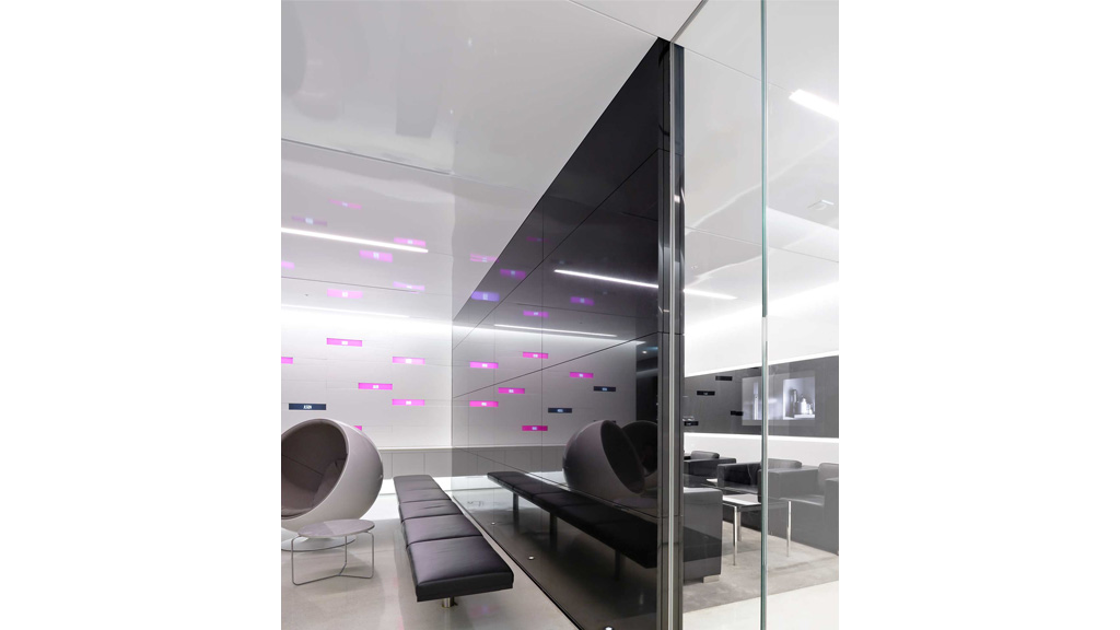 A room with a glass wall and a couch and a chair.