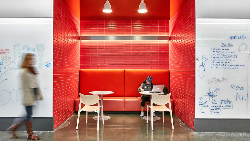 A woman standing in front of a man sitting at a table.