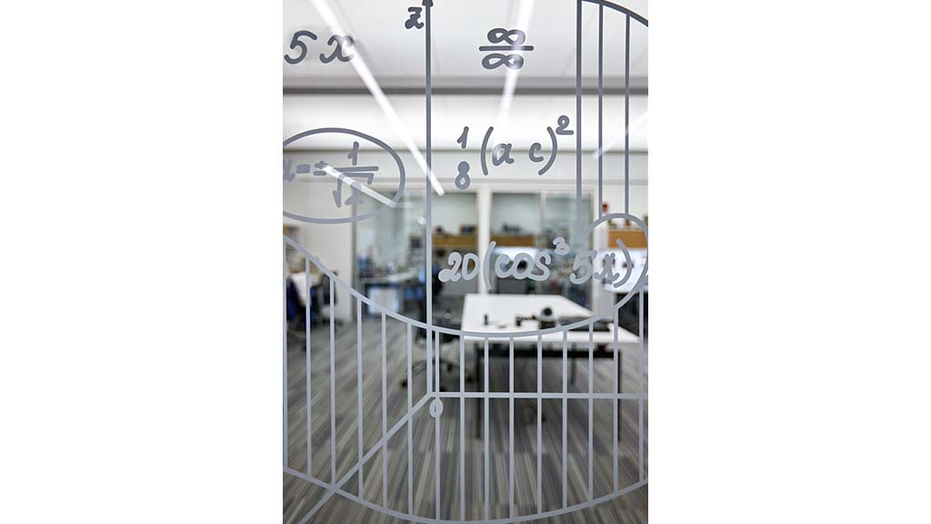 A glass window with a railing and a table and chairs in the background.