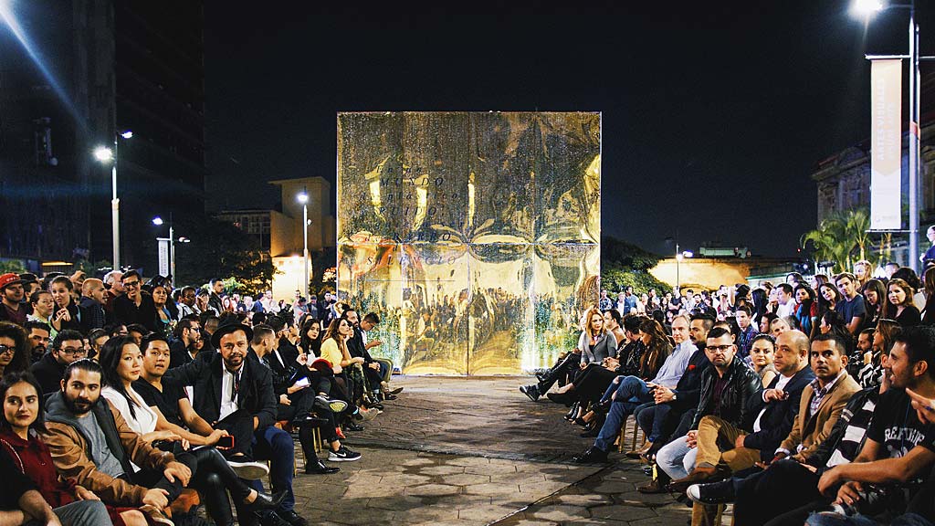 A group of people sitting in a row in front of a stage.