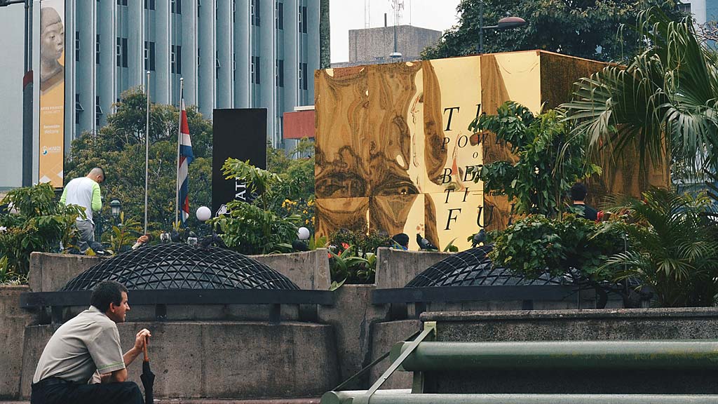 A person sitting on a bench next to a large sculpture.