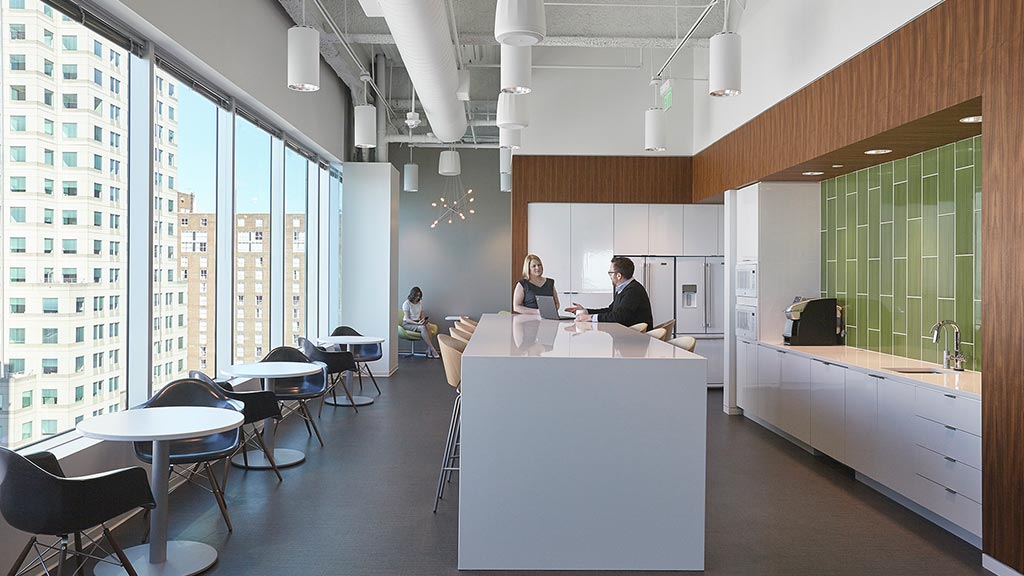 A couple of people sitting at a table in a room with windows.