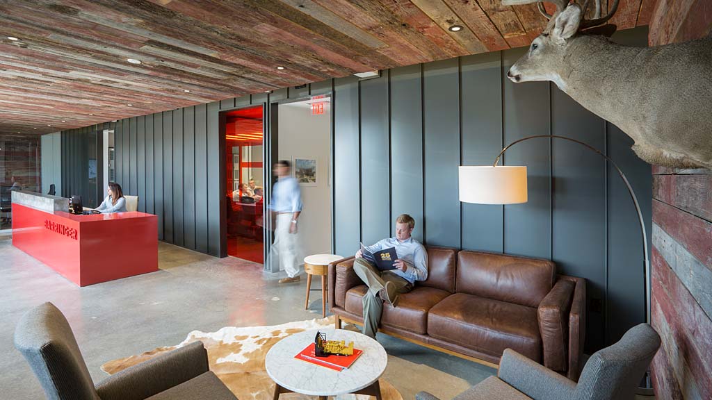 A person sitting on a couch in a room with a dinosaur statue.