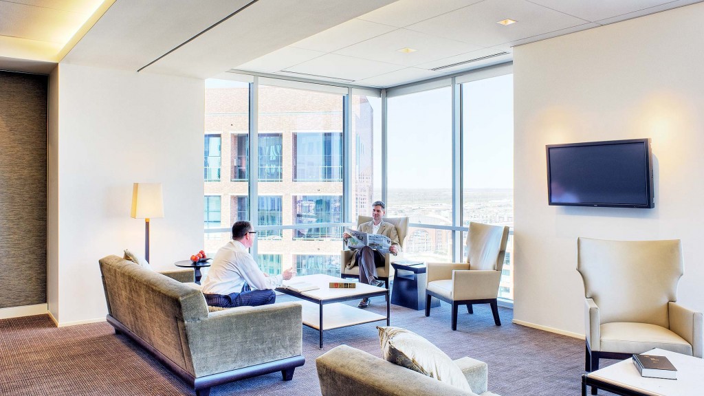 A couple of men sitting in a living room with a tv and a large window.