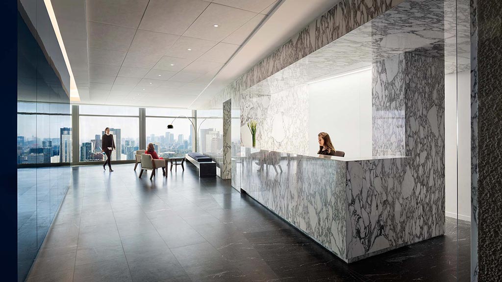 A person sitting on a bench in a large room with a large window.