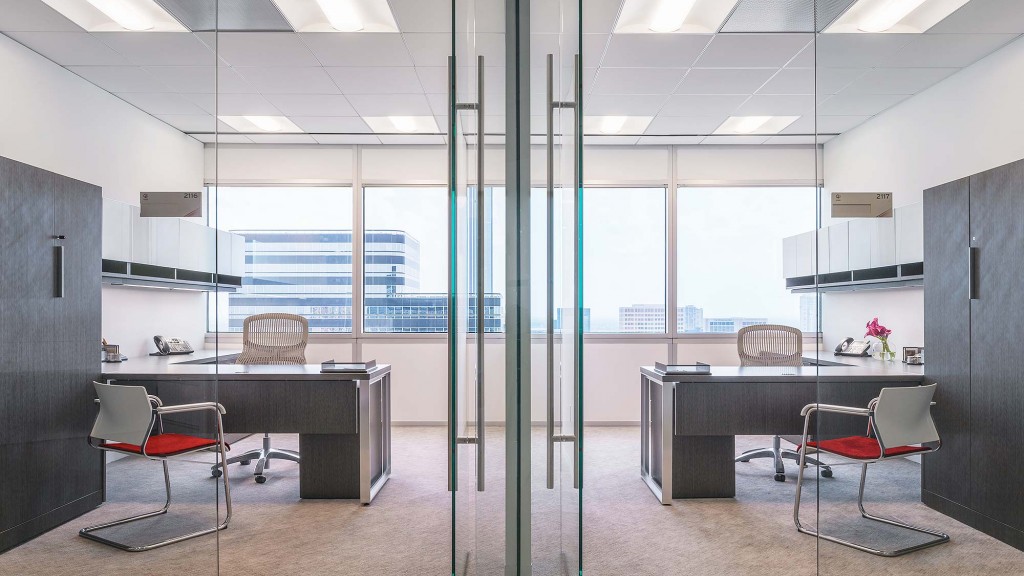 A room with a table chairs and a window with a view of the city.