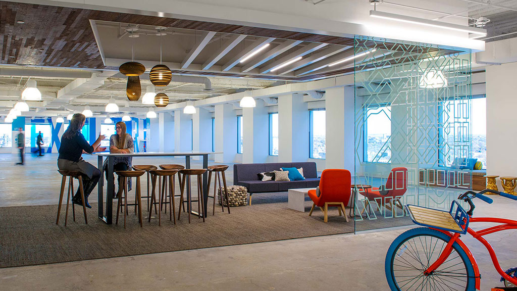 A couple of people sitting at a table in a room with a bike and chairs.