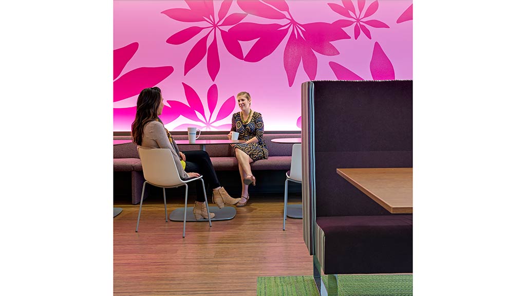 A person sitting on a chair next to a person sitting at a desk.