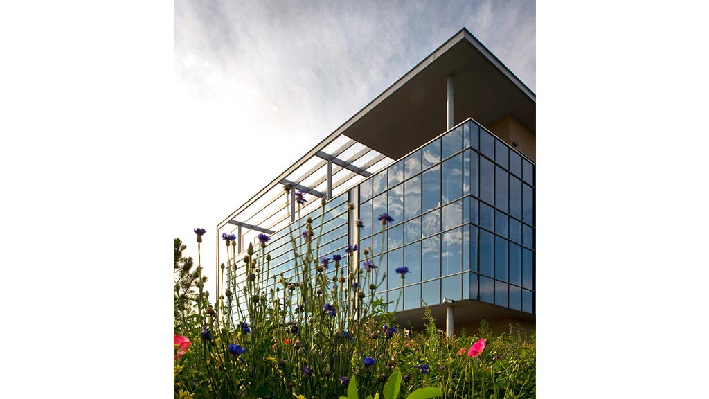 A building with a glass wall and flowers in front of it.