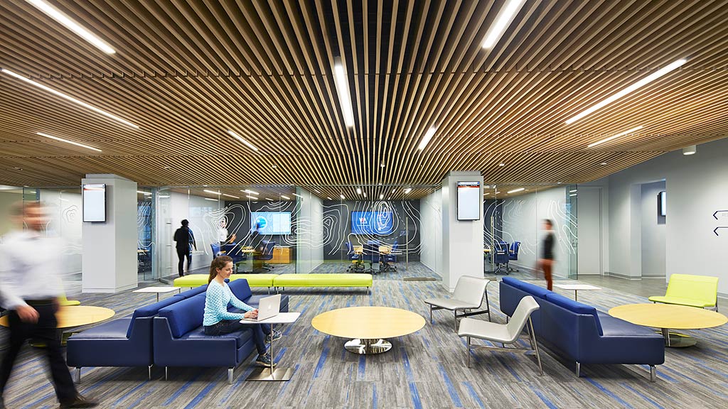A person sitting at a table in a room with blue couches.