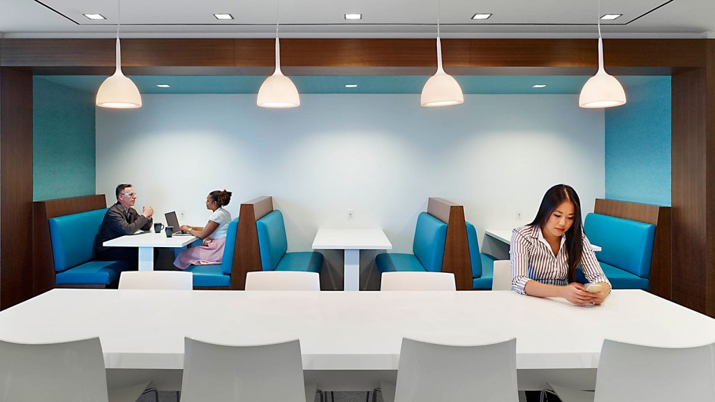 A group of people sitting at a table in a room with blue chairs.