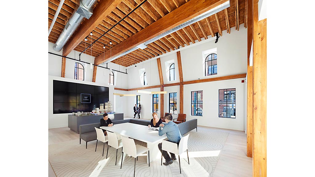 A group of people sitting around a table in a room with a wood ceiling.
