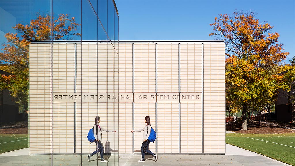A couple of women walking by a large white building with trees.