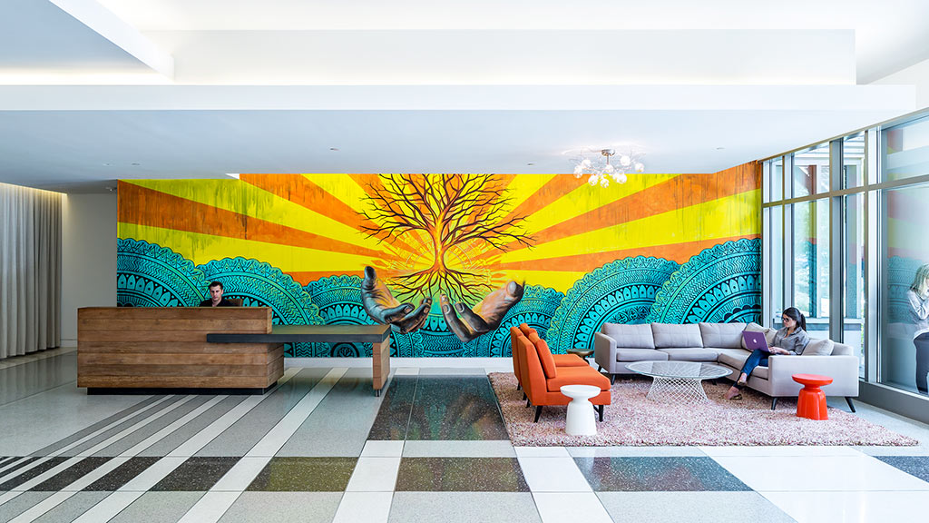 A person sitting on a couch in a room with a large painting.