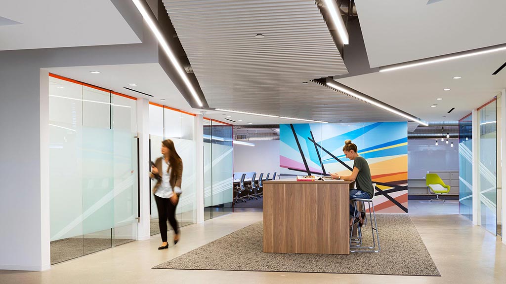 A man and a woman in a room with a large screen.