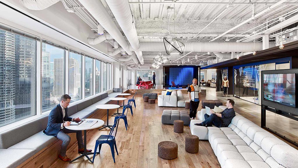 A group of people sitting in a room with a large screen.