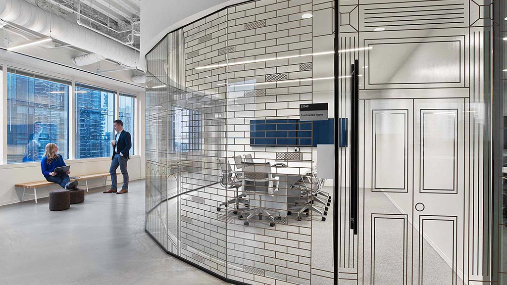A man and a woman in a room with a large glass wall.