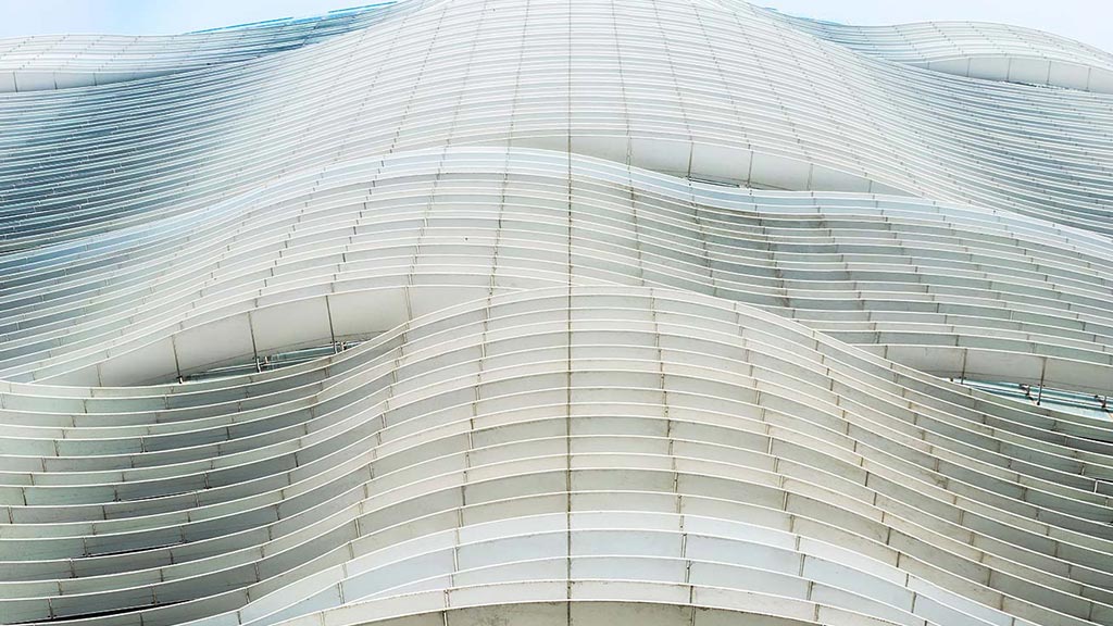 A large white building with many windows with Aqua in the background.