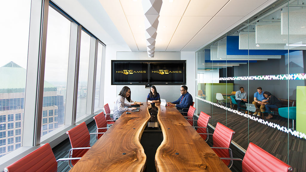 A group of people sitting at a table in a room with large windows.