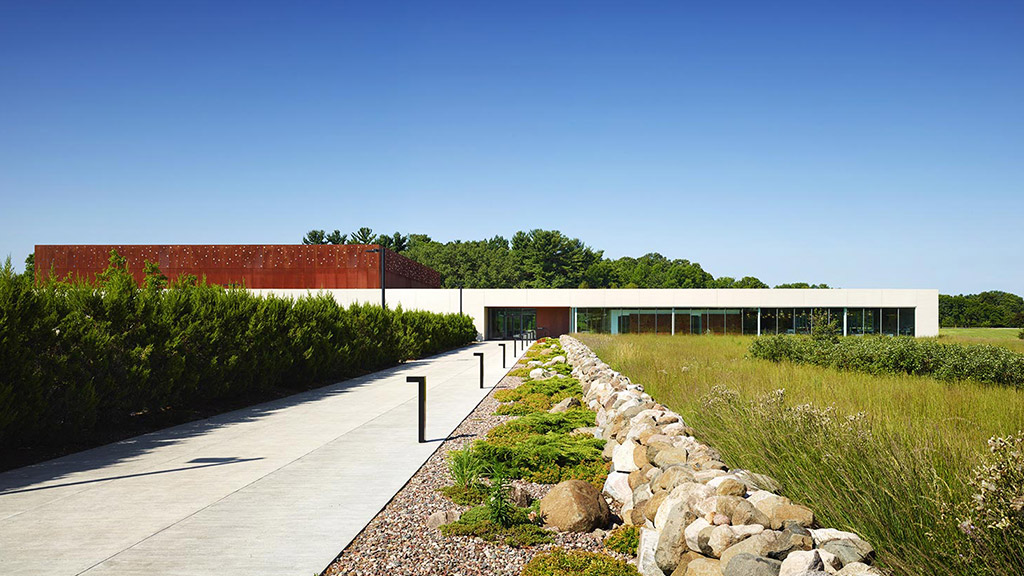 A building with a walkway and bushes.