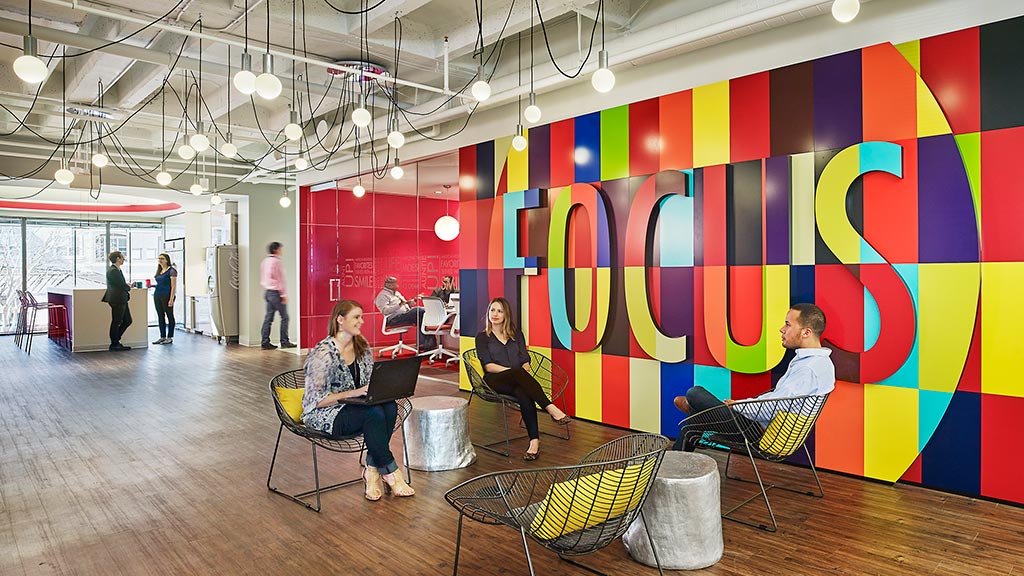 A group of people sitting in chairs in a room with a colorful wall.