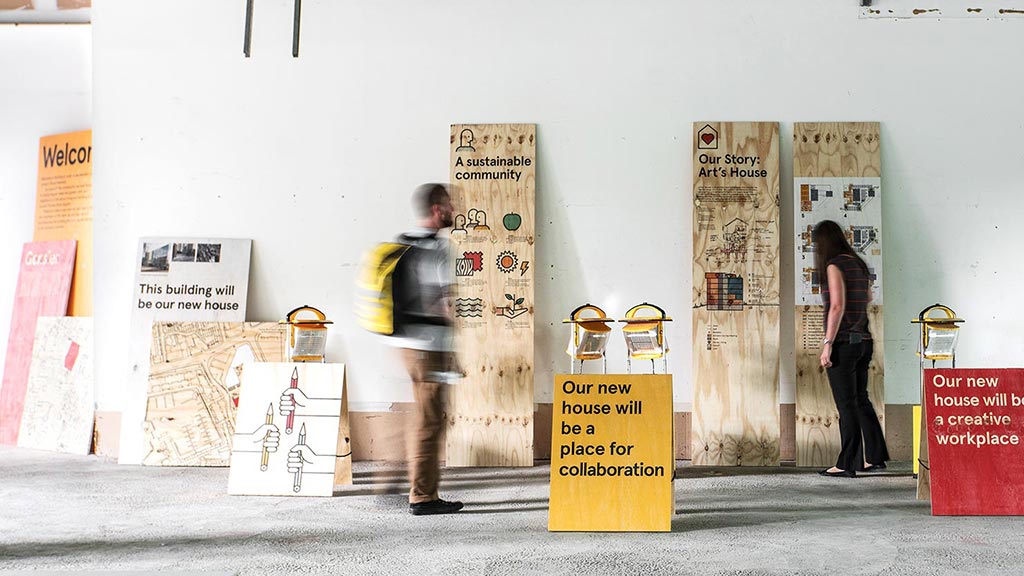 A group of people standing next to a wall with signs.