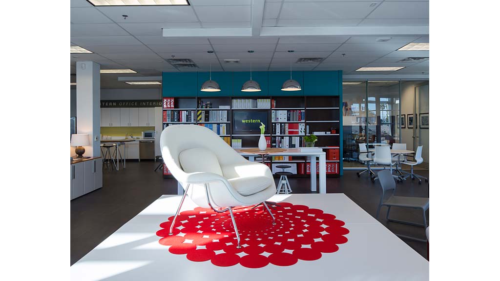 A room with a red and white lounge chair and a table with a red and white cloth on.