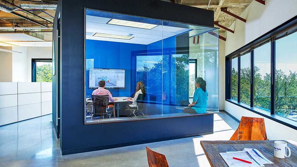 A group of people sitting at a table in a room with large windows.