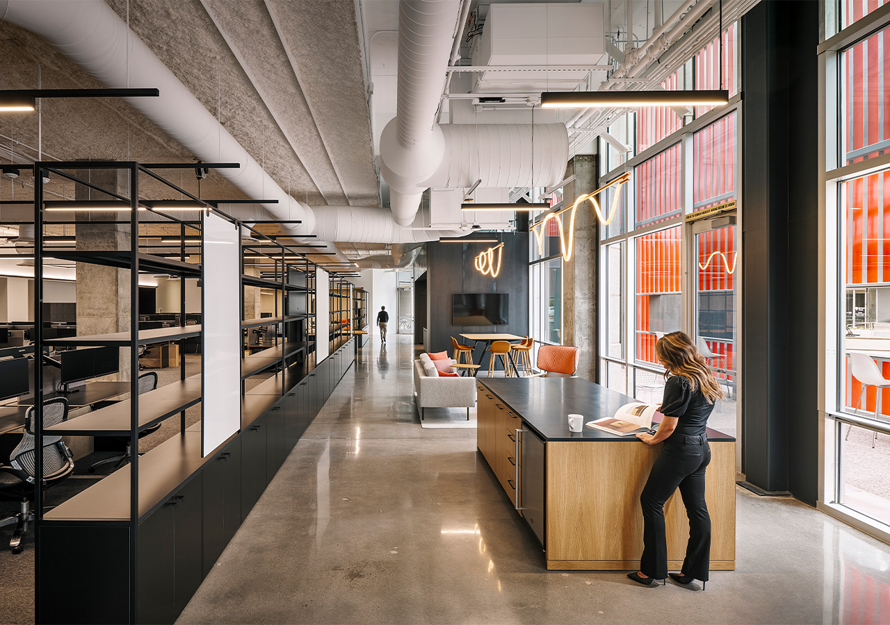 A person standing at a desk in a large office.