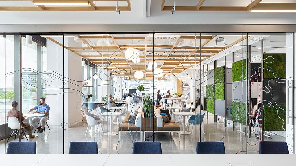 A group of people sitting at a table in a room with glass walls.