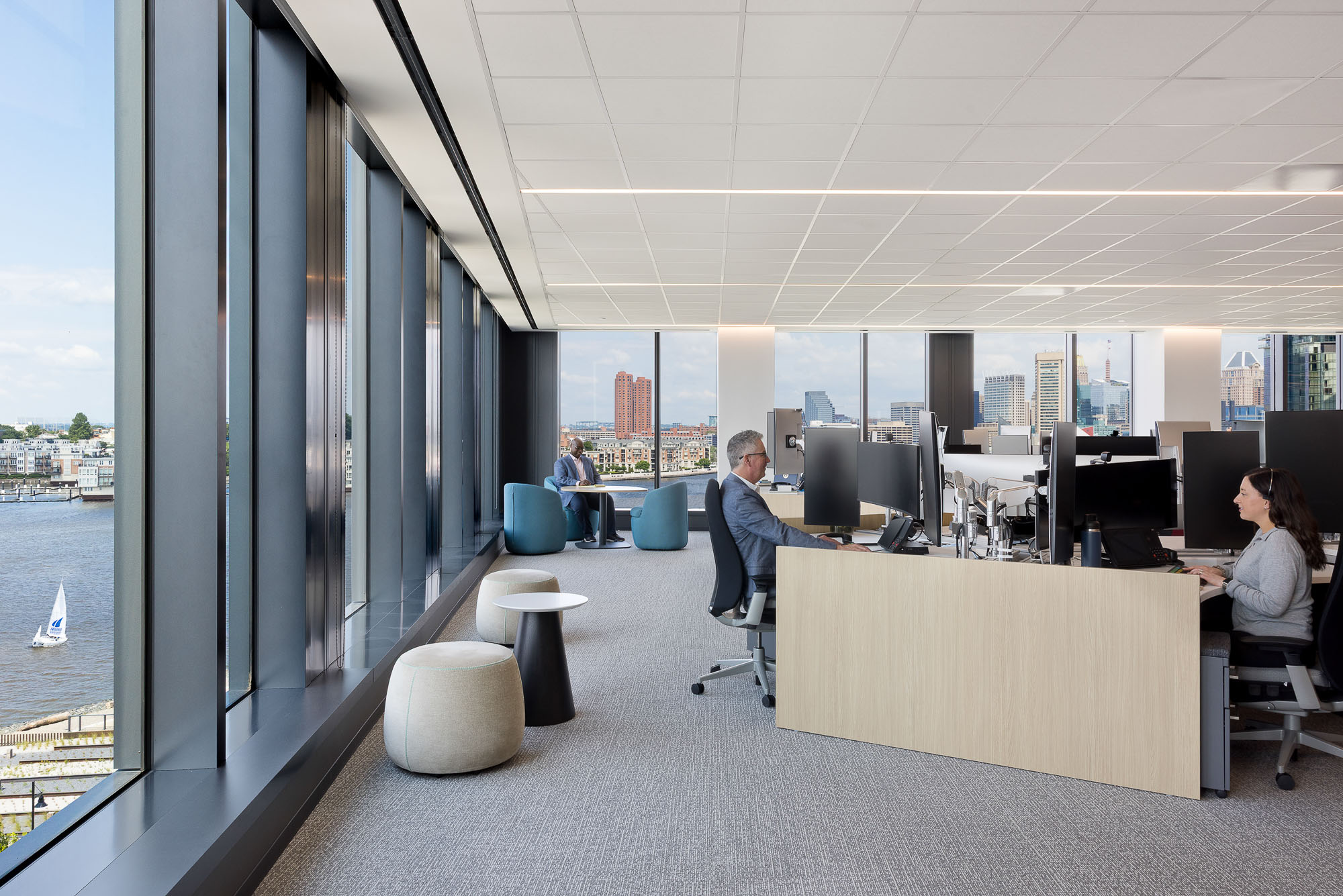 A group of people sitting at a desk in a room with large windows.