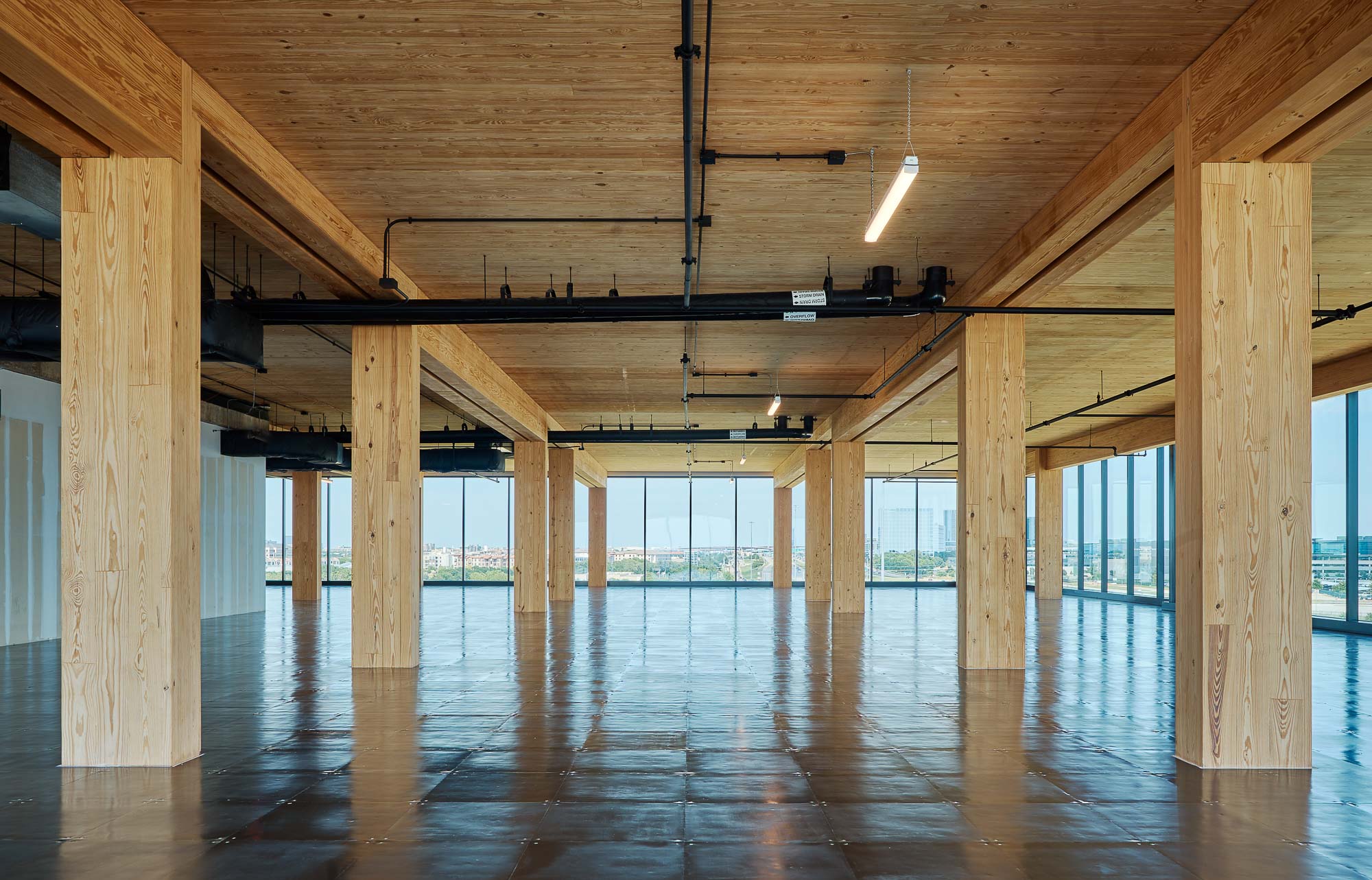 A large wooden room with a wood floor and a large window.