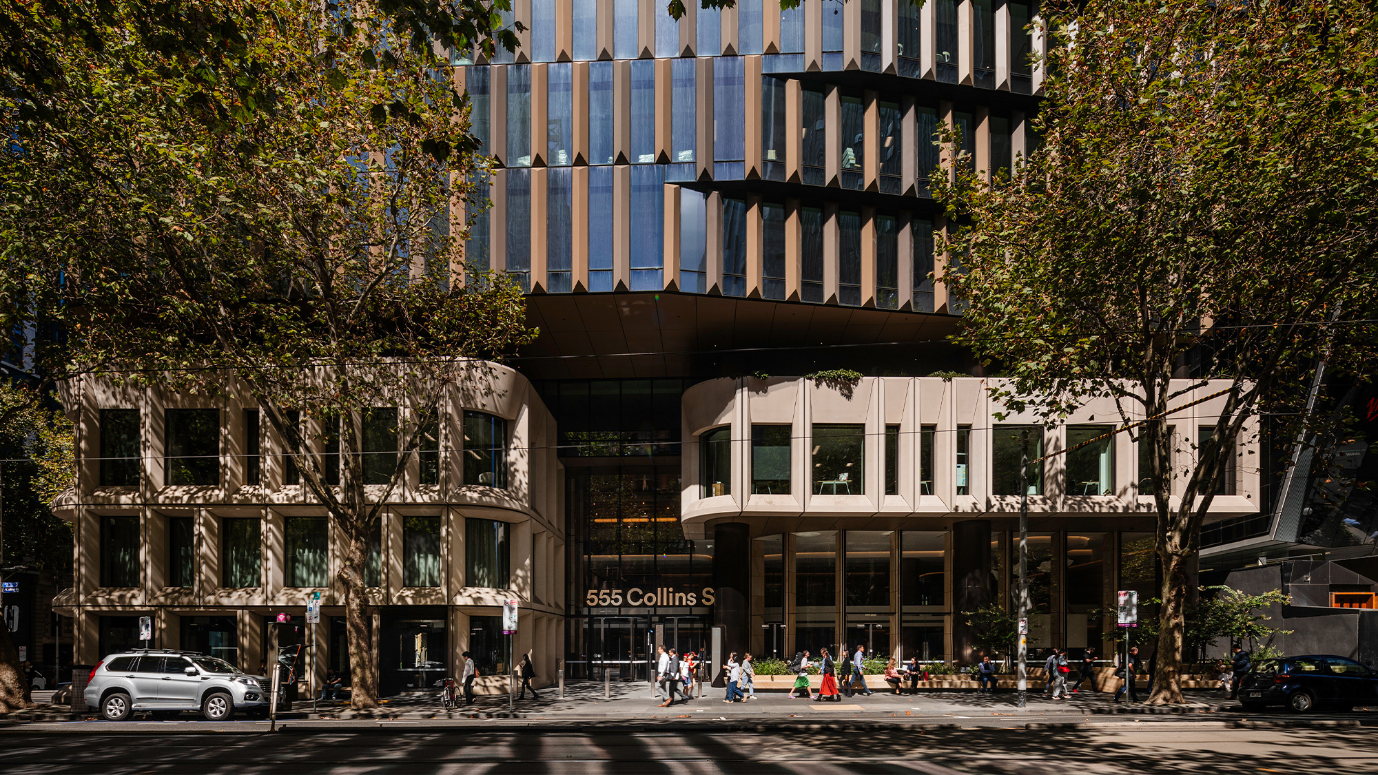 A street with cars and people on it next to a building.