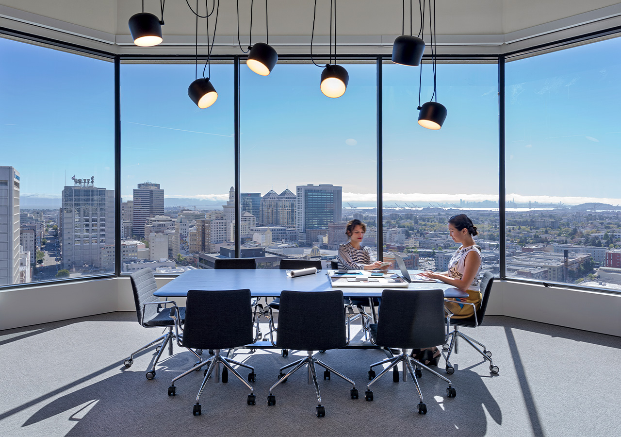 A couple of people sitting at a table with a view of a city.