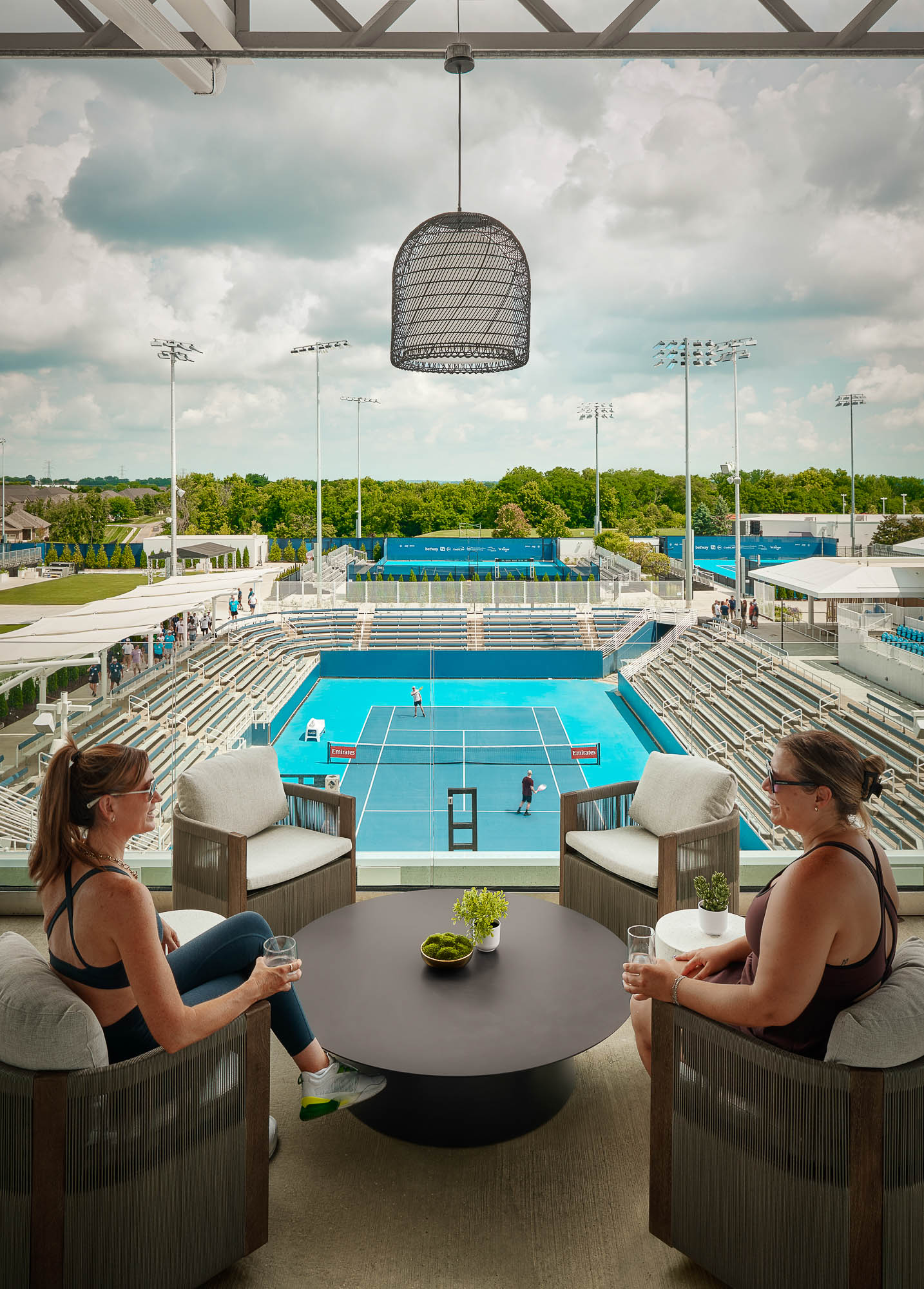 A couple of women sitting at a table by a pool.